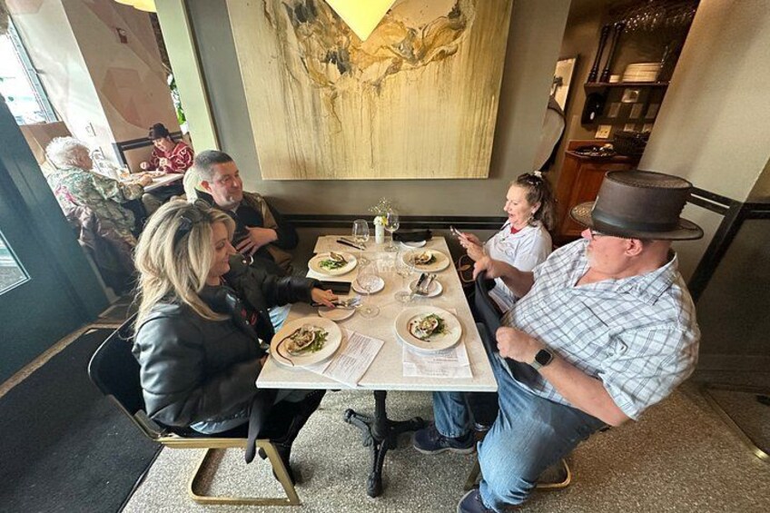 Un grupo de personas cenando en un restaurante con un cuadro grande en la pared. 3