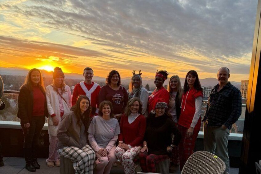 A group of people on a rooftop at sunset with a cityscape in the background. 2