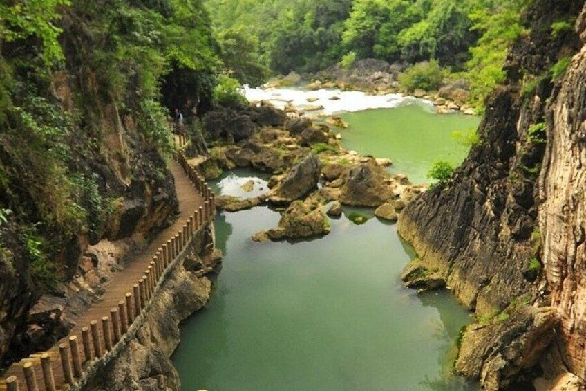 A river with a wooden walkway along a rocky cliff. 4