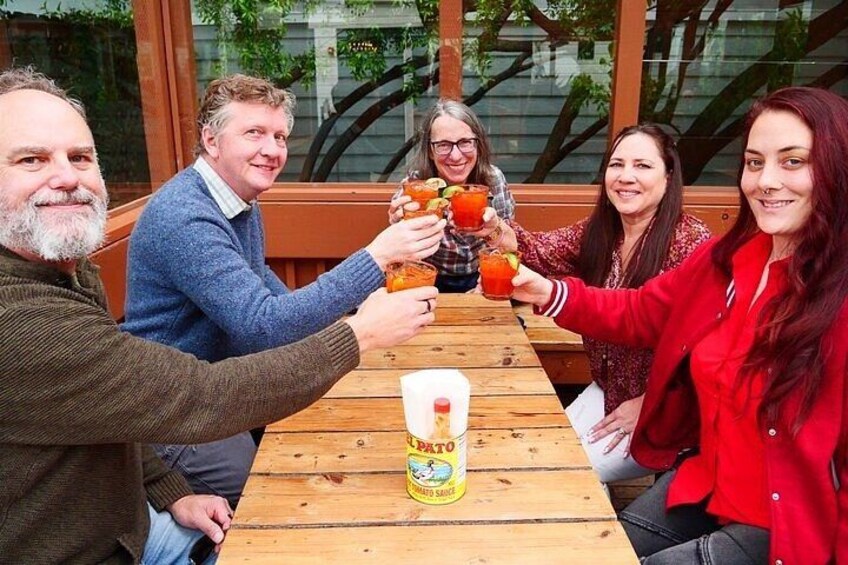 A group of people toasting with drinks at a wooden table with a can of soda. 2