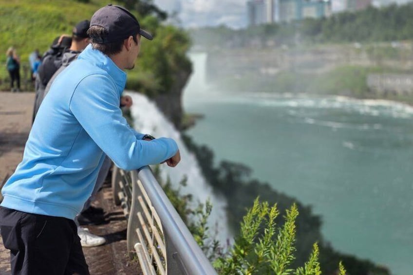 A person in a blue jacket standing on a bridge overlooking a river. 3