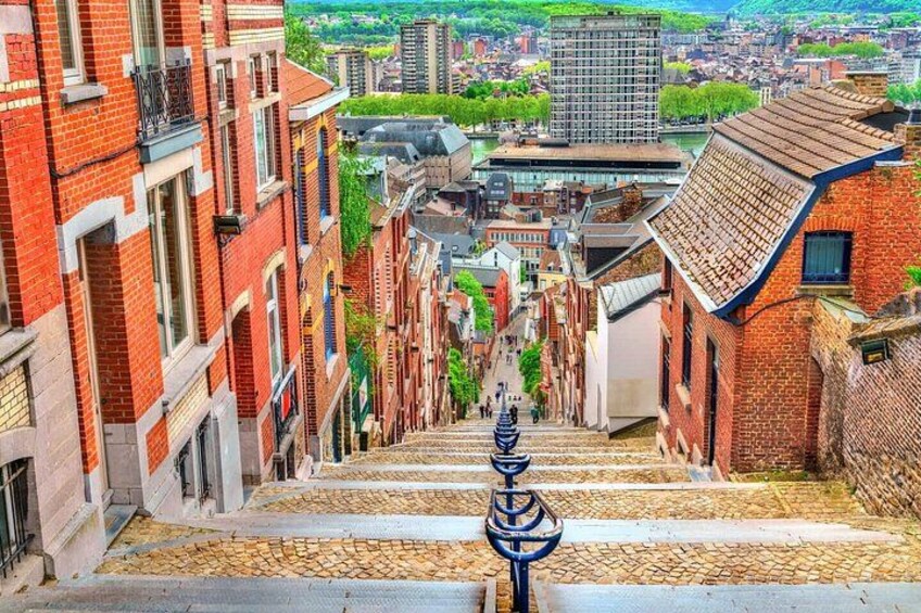 A cobblestone street flanked by red brick buildings, leading down a steep incline. 4