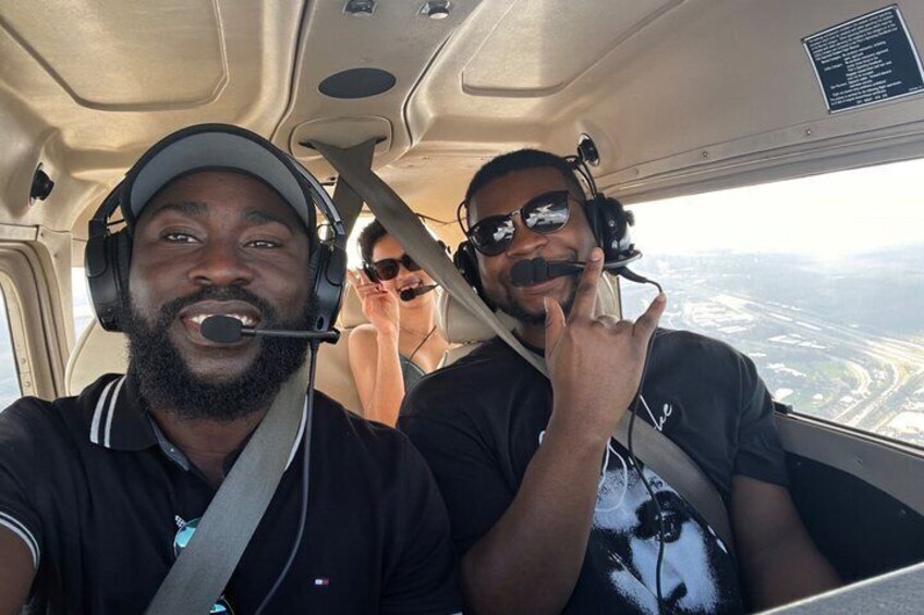 Two individuals in a cockpit with a view of a landscape outside. 4