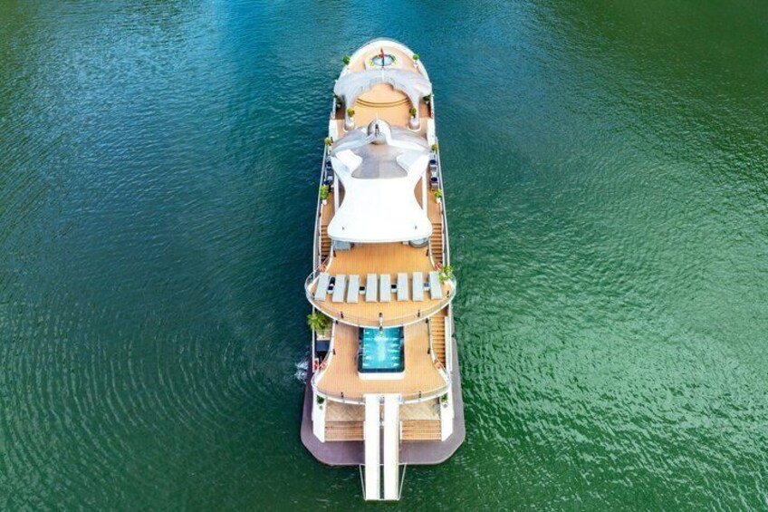 A large cruise ship with a swimming pool and lounge chairs on deck. 2
