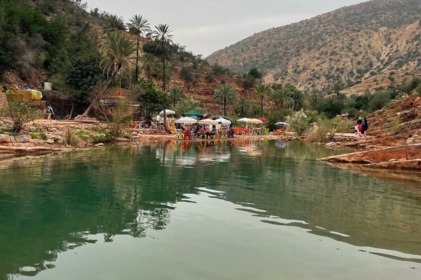 A calm river with people and umbrellas in the background. 2