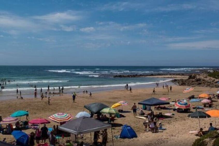 A beach with people, tents, and colorful umbrellas. 4