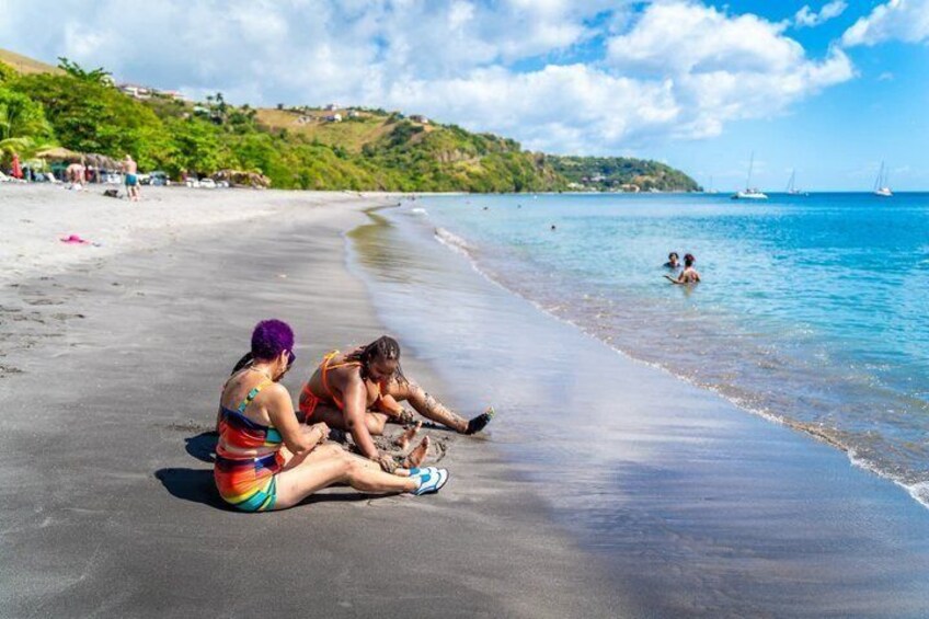 Una playa con gente sentada sobre la arena, cielo despejado y veleros en el agua. 3