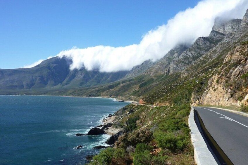 A coastal road with a mountain backdrop, clear skies, and a view of the sea. 4