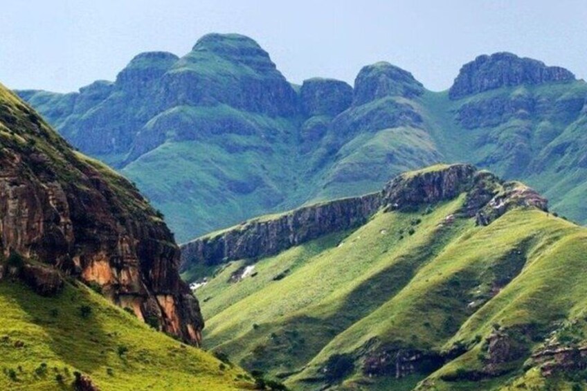 A mountainous landscape with green hills and rocky cliffs. 3