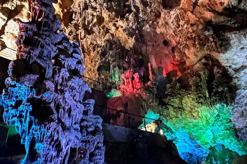 A cave with colorful stalactites and stalagmites illuminated by artificial lighting. 5