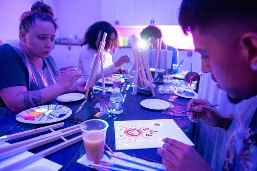 People painting at a table with art supplies. 2