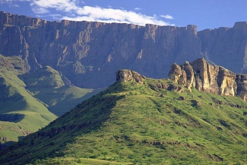 A mountainous landscape with green slopes and rocky cliffs. 1
