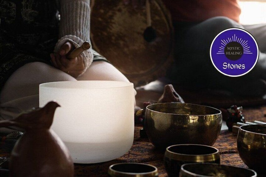 A person sitting with a white bowl, surrounded by various brass bowls and a small figurine. 2