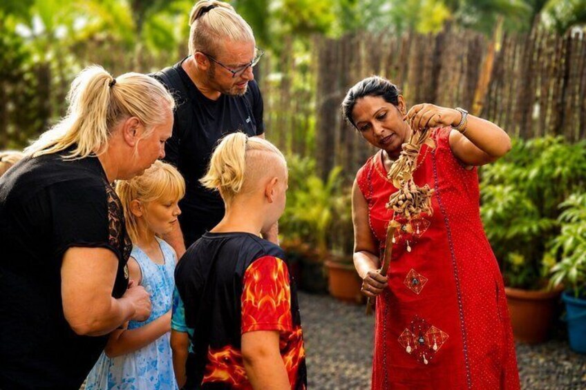 A group of people outdoors, some wearing casual clothing, and one person in a red traditional dress holding a decorative item. 1