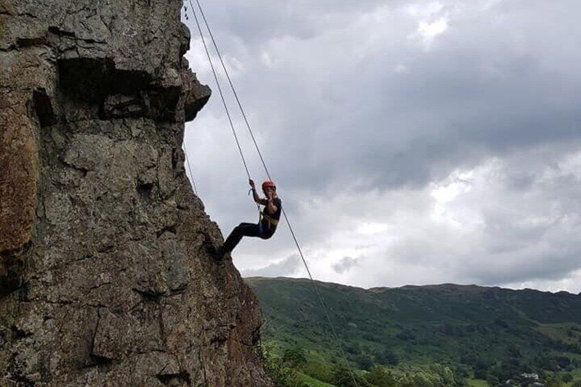 A person rappelling down a rocky cliff with a harness and ropes. 5