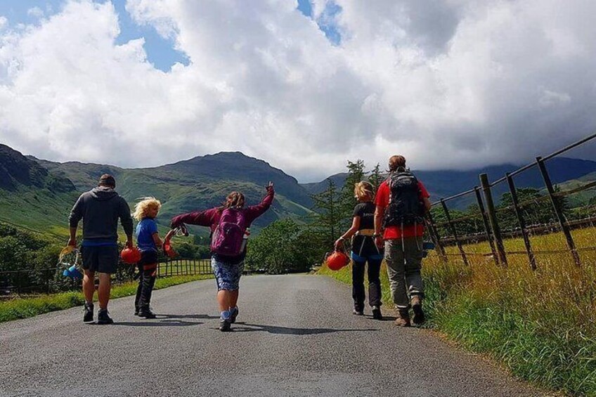 A group of people walking on a road surrounded by mountains. 4
