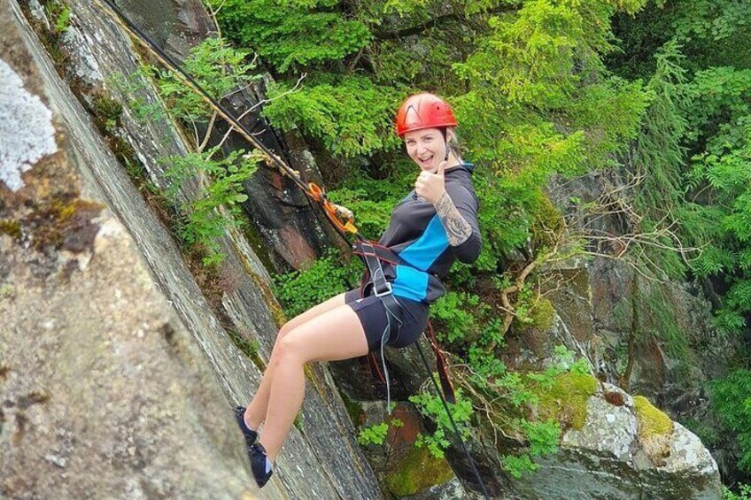 A person rappelling down a rocky cliff with a harness and helmet. 1