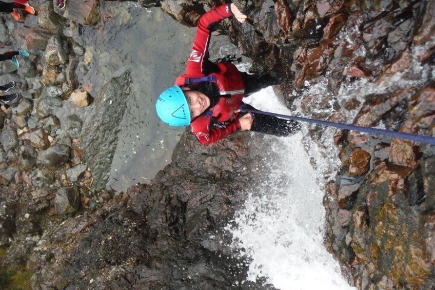 A person rappelling down a rocky cliff. 1