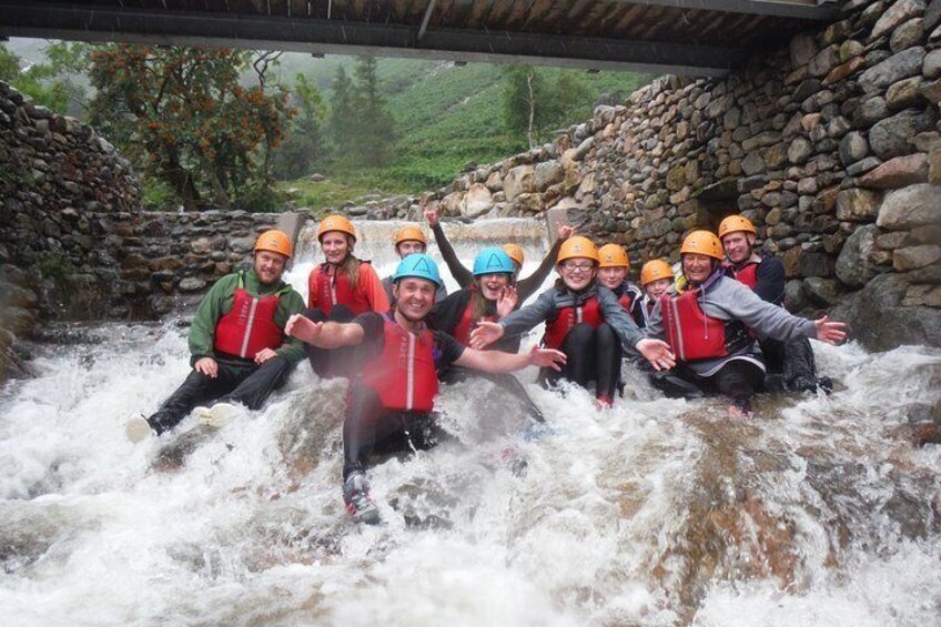 A group of people rafting on a river under a stone bridge. 3