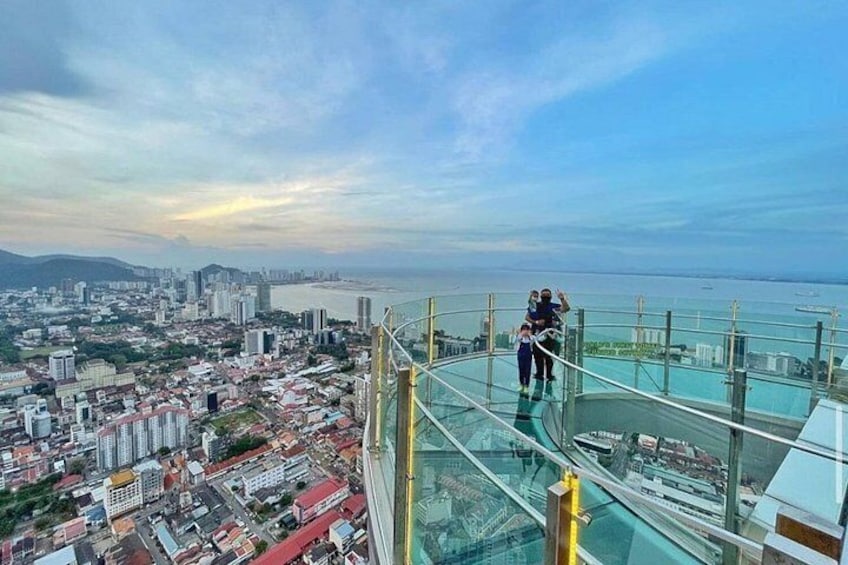 A glass bridge with a cityscape and beach in the background. 5