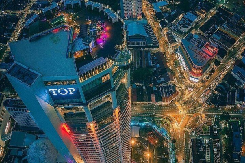 A cityscape at night with illuminated buildings, including a prominent 'TOP' sign on a skyscraper. 2