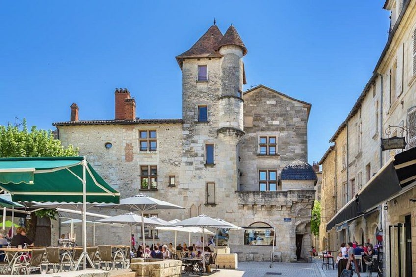 A historic stone building with a tower, outdoor seating, and a clear blue sky. 5