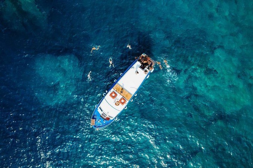 A boat with people on board, floating on clear blue water. 1