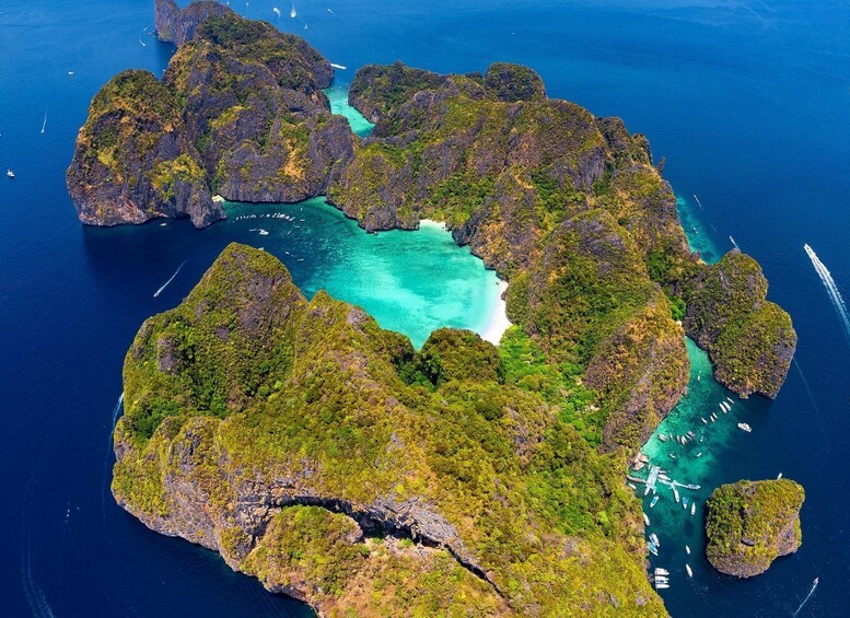An aerial view of a lush, green island surrounded by clear blue waters with several boats. 2