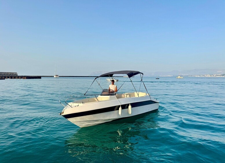 A small motorboat on calm water with a clear sky and distant land. 2