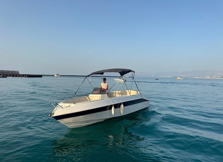 A small motorboat with a canopy on the water near a pier. 3