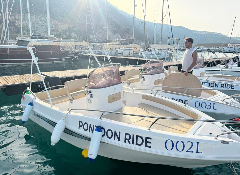 A marina with several boats docked, including a white boat named 'PONZON RIDE' with the number '002L' on its side. 1