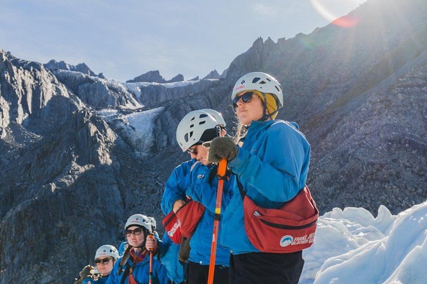 A group of people wearing helmets and climbing gear on a snowy mountain. 3