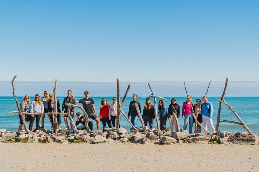 A group of people standing on a beach with a clear sky and calm sea in the background. 5