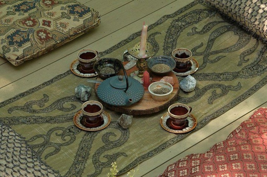 A traditional tea setting with teapots, cups, and decorative items on a patterned rug. 2