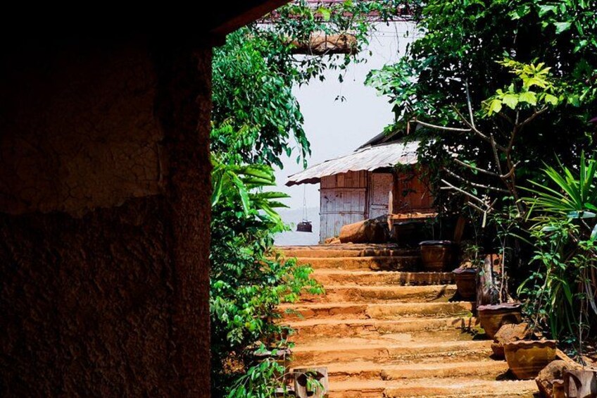 A stone staircase leading to a traditional wooden house surrounded by lush greenery. 3