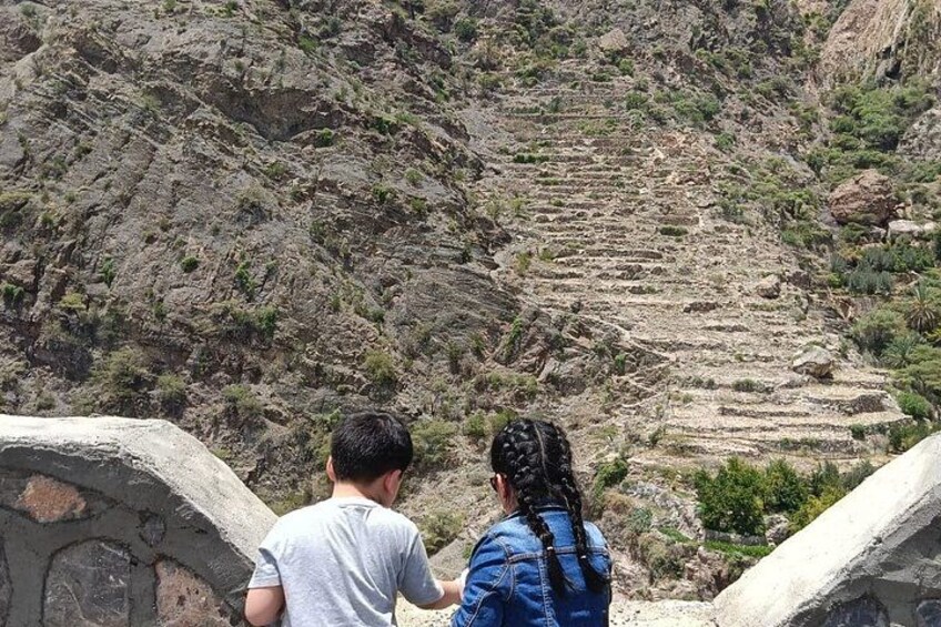 Two people overlooking terraced agricultural fields in a mountainous area. 5