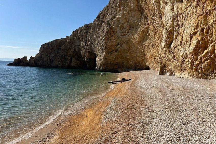 A pebble beach with a rocky cliff and calm sea. 3