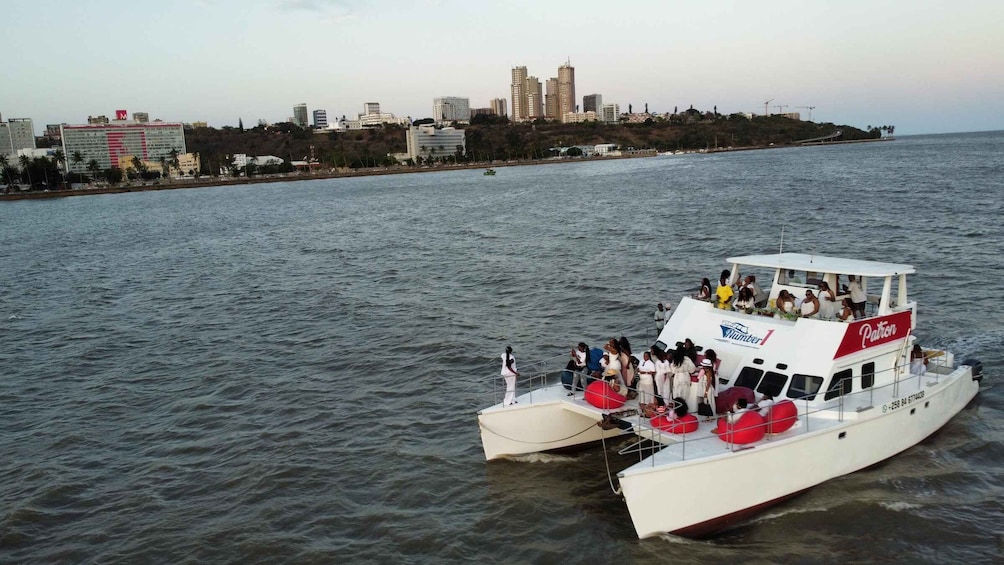 A white boat with red accents on the deck, docked at a pier with a city skyline in the background. 5