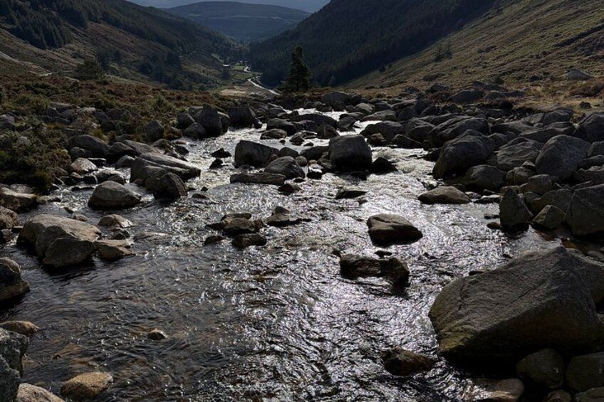 A river with large rocks, surrounded by hills and a valley. 2