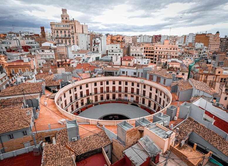 A historic bullring surrounded by densely packed urban buildings. 5