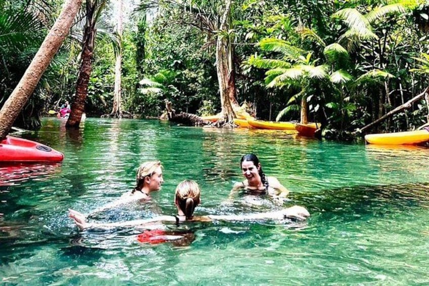 Personas nadando en un río tropical cristalino rodeado de exuberante vegetación. 1