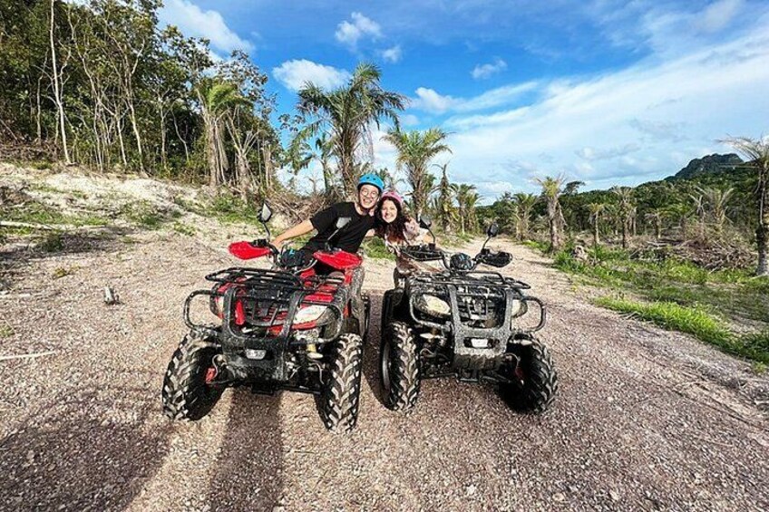 Dos vehículos todo terreno en un camino de tierra, con palmeras y una montaña al fondo. 2