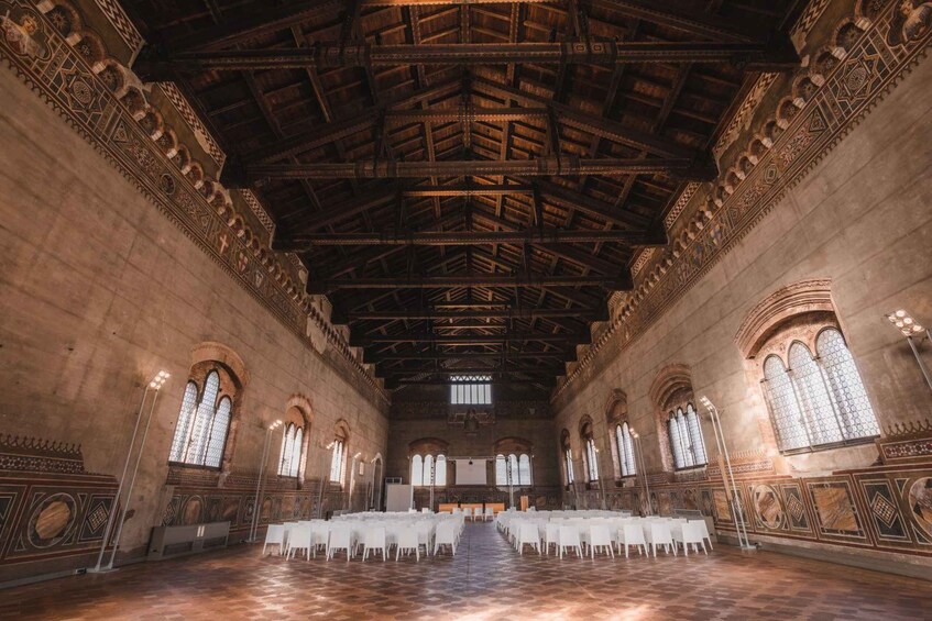 A large hall with a high ceiling, arched windows, and patterned walls. 4