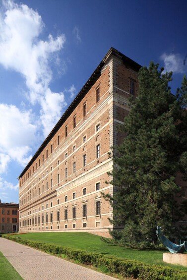 A large brick building with multiple windows and a tree in front. 2