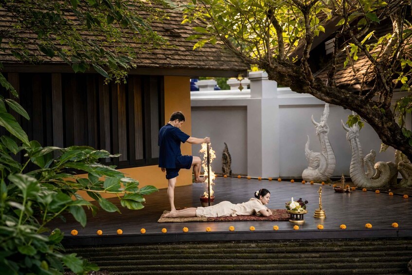 A person performing a ritual with a fire on a stage, surrounded by statues and marigold flowers. 1