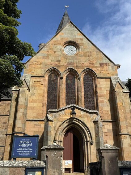 Dornoch Cathedral with a prominent entrance, a clock tower, and a clear blue sky. 2