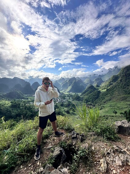 A person standing on a rocky outcrop with a mountainous landscape in the background. 5