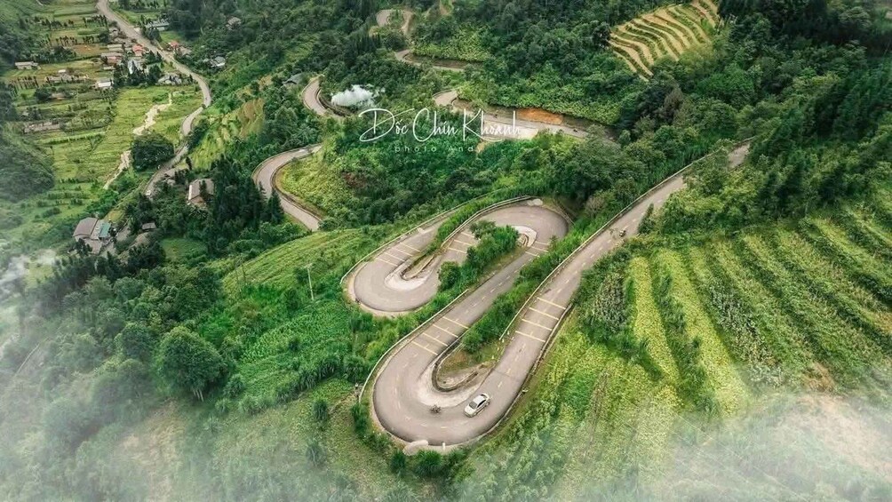 A winding road through a lush green landscape with terraced fields. 1