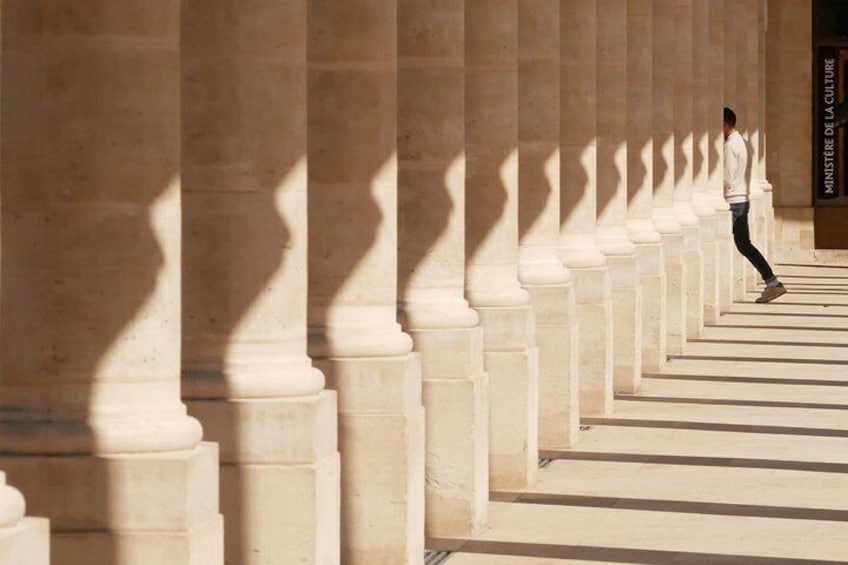 A person walking down a corridor with tall columns. 2
