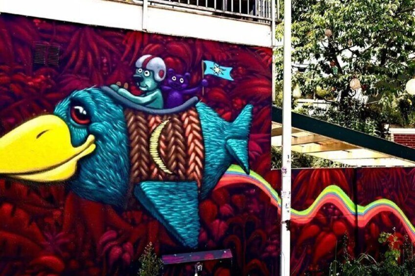 A colorful mural of a fish with a character on its back, set against a red background. 4